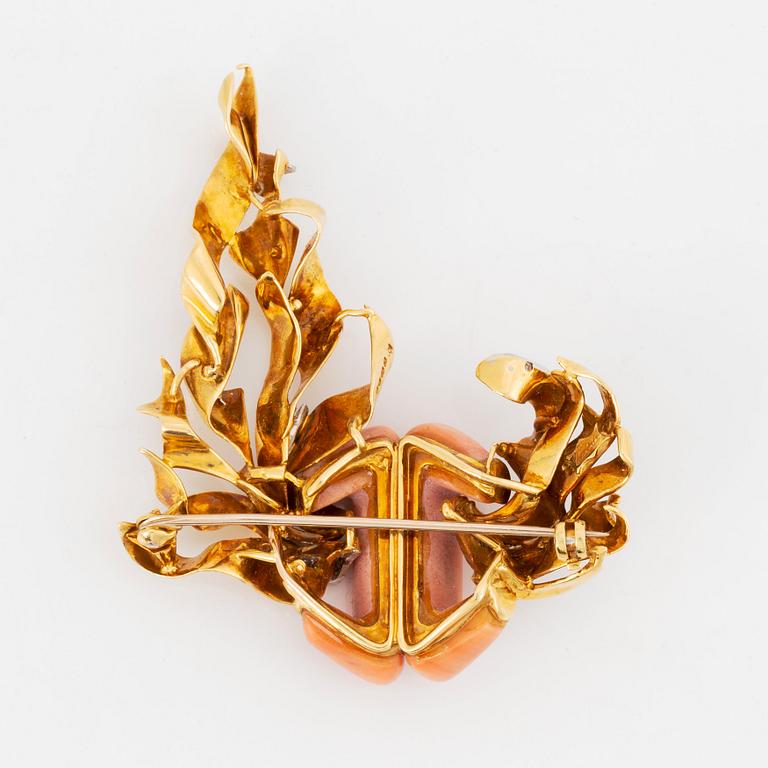 A Kutchinsky brooch in 18K gold set with coral and round brilliant-cut diamonds.