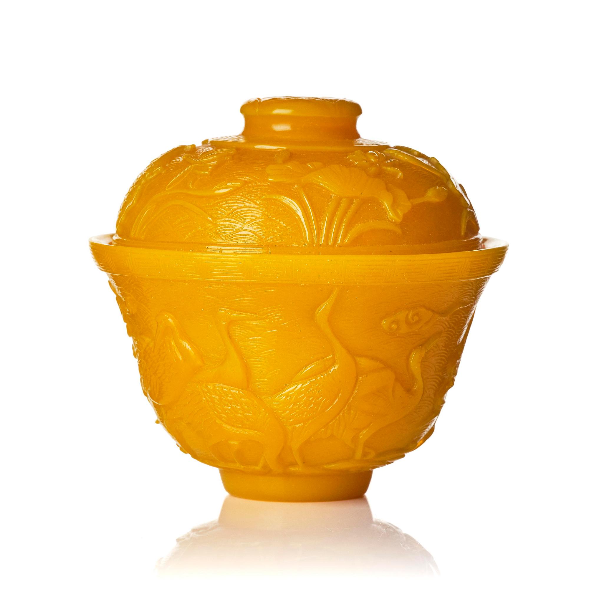A well carved yellow glass 'crane and lotus' cup with cover, presumably late Qing dynasty.