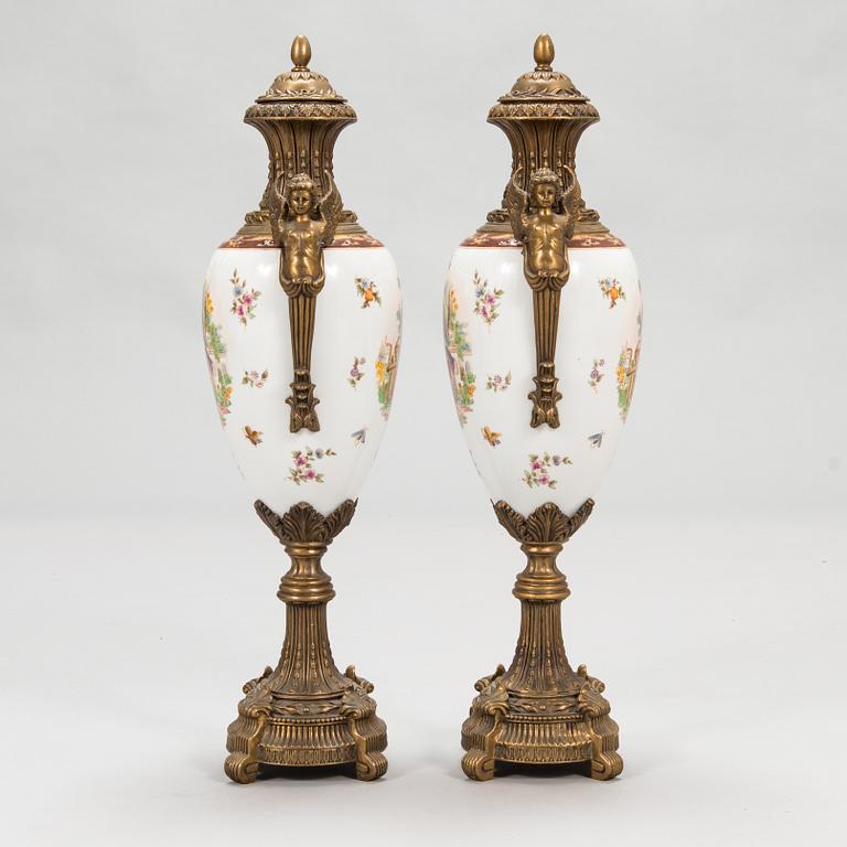 A pair of urns with lids, in bronze and porcelain, 20th century.