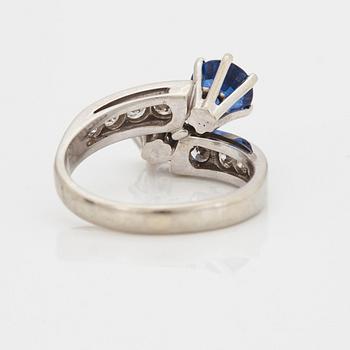A CROSS-OVER RING set with a round mixed-cut sapphire and round brilliant-cut diamonds.