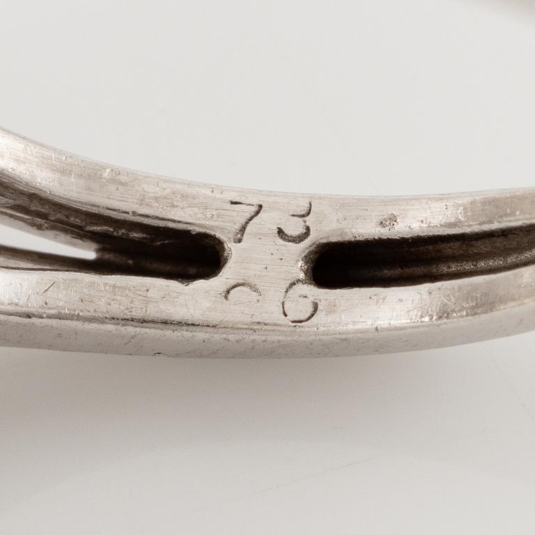 A platinum ring set with a pear-shaped yellow diamond and round brilliant-cut diamonds.