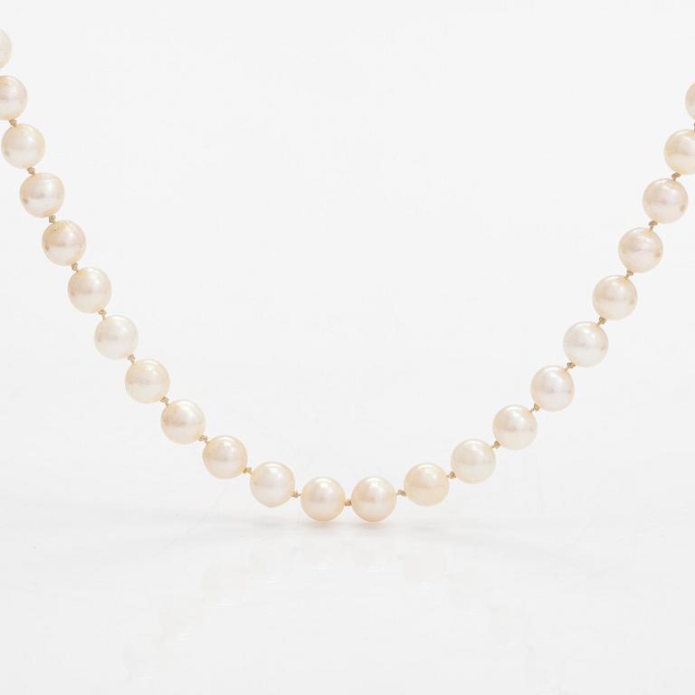 A cultured pearl necklace, clasp 18K gold with emerald and small diamonds.