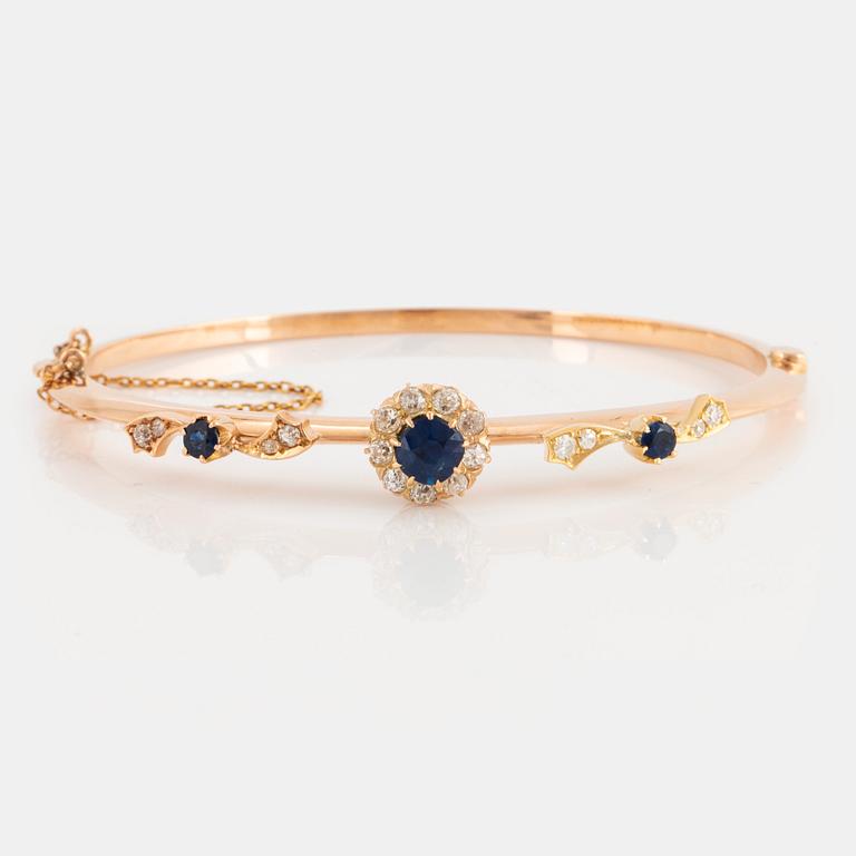 An 18K gold bangle set with faceted sapphires and old-cut diamonds.