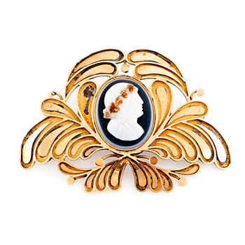 An 18K gold brooch set with a hard stone cameo.