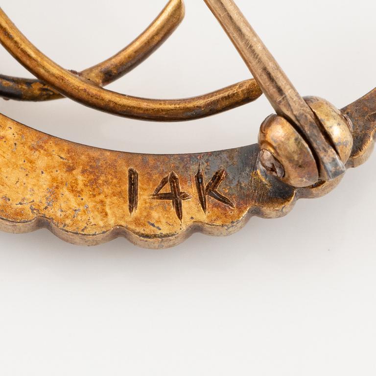 A brooch in the form of a crescent moon in 14K gold  with enamel and rose-cut diamonds.