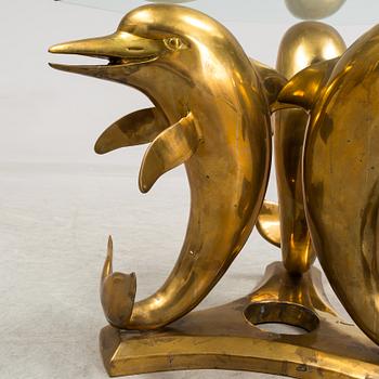 A brass and glass coffee table decorated with dolphins.