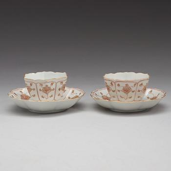 A pair of 'rouge de fer and gold' cups with stands, Qing dynasty, Qianlong (1736-95).