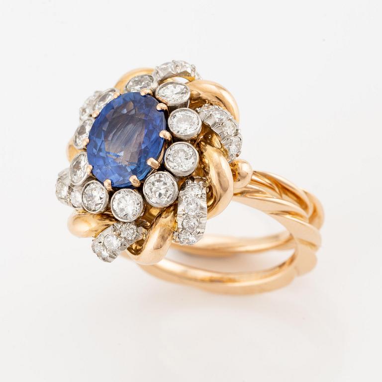 An 18K gold  ring with a sapphire and round brilliant-cut diamonds.