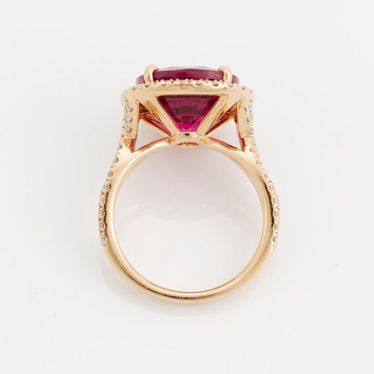 An 18K gold ring set with a faceted pink tourmaline and round brilliant-cut diamonds.