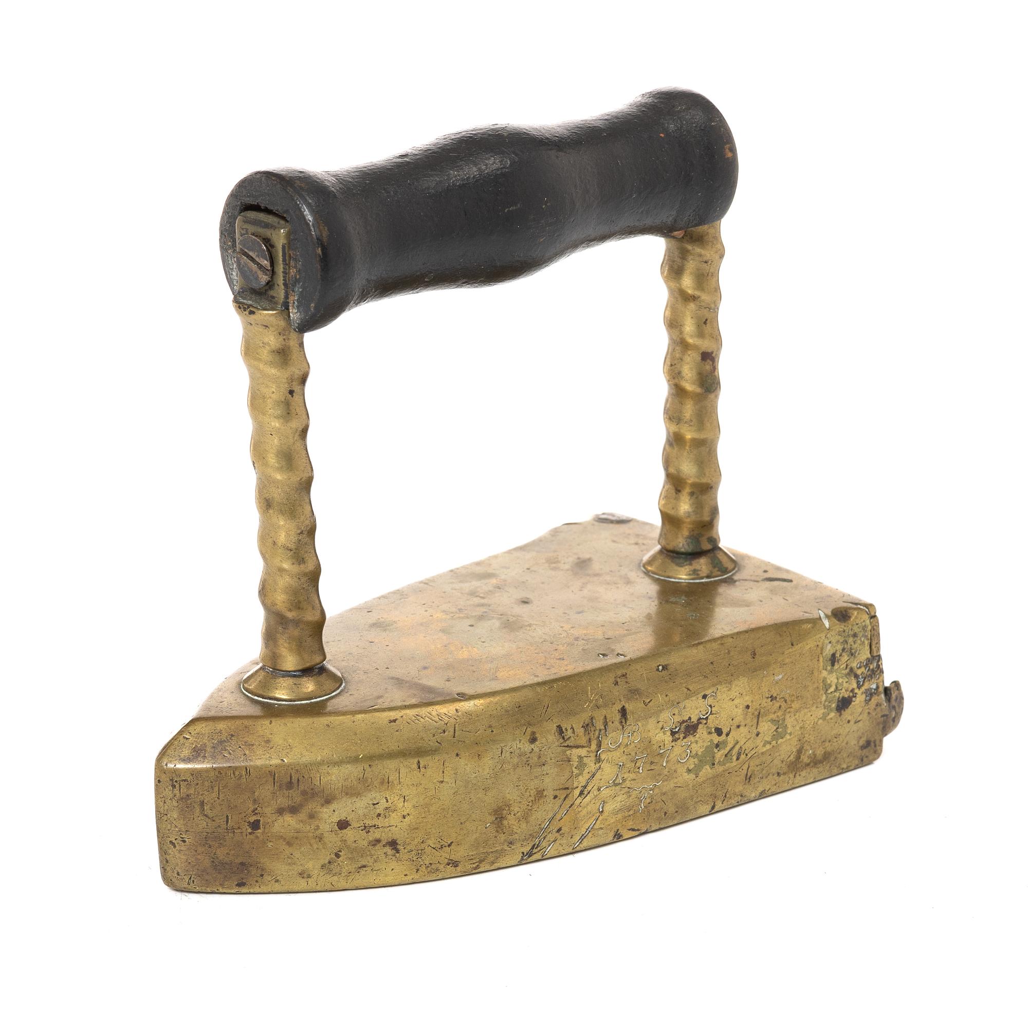 A brass clothes' iron, dated 1773.