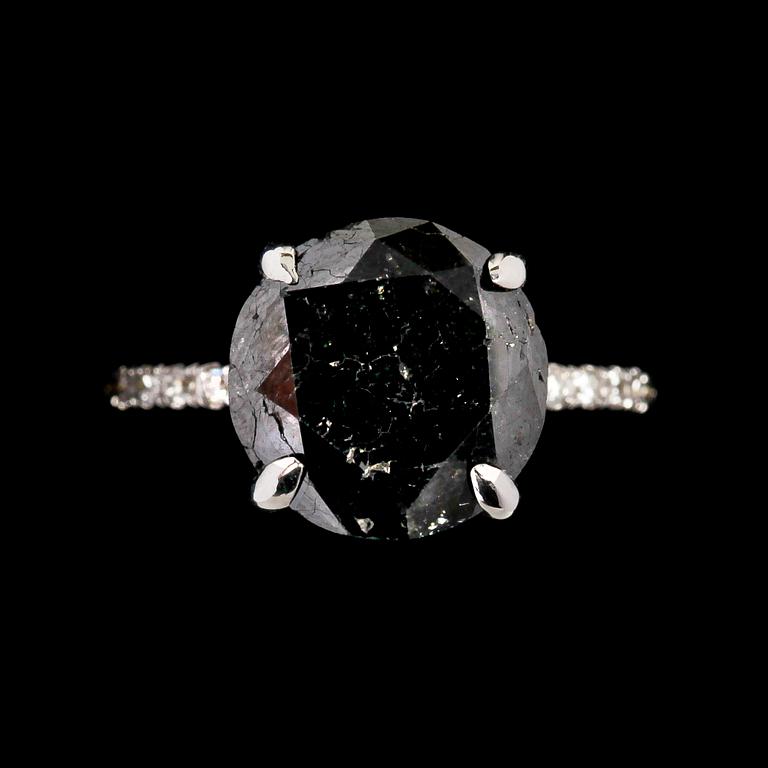 RING, svart briljantslipad diamant, 6.40 ct samt små vita briljantslipade diamanter, tot. 0.40 ct.