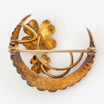 A brooch in the form of a crescent moon in 14K gold  with enamel and rose-cut diamonds.