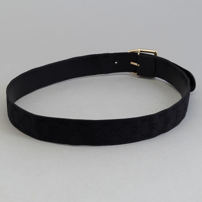 A blach monogram belt by Gucci.