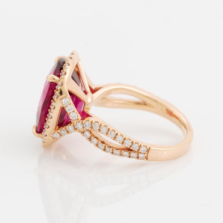 An 18K gold ring set with a faceted pink tourmaline and round brilliant-cut diamonds.