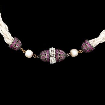 A necklace of cultured pearls and seed pearls with a silver clasp decorated with probably synthetic rubies.