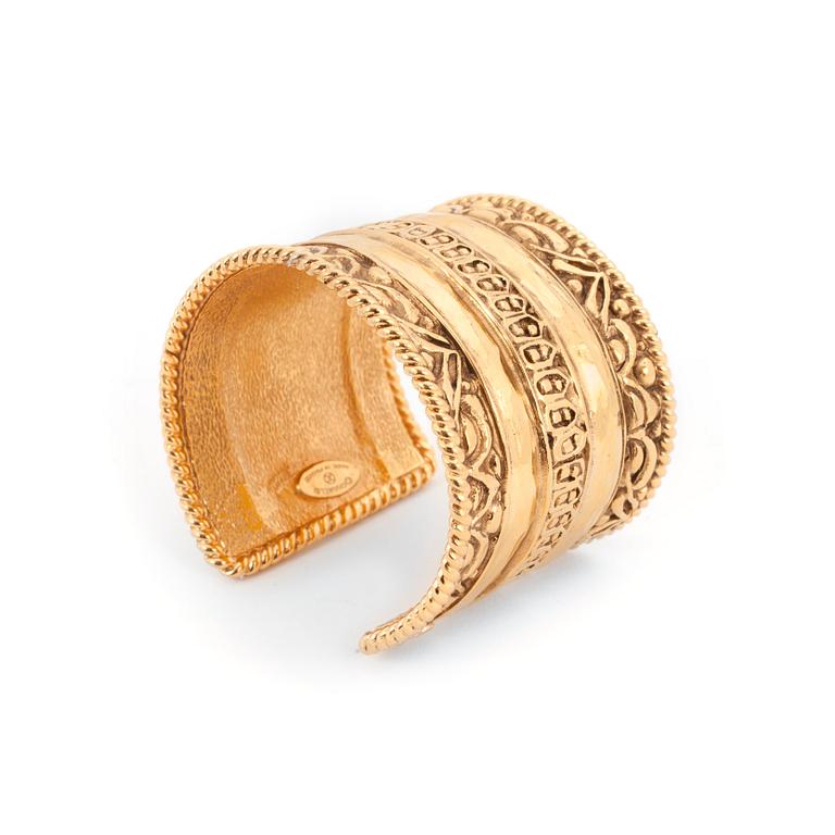 CHANEL, a gold colored metal cuff braclet.