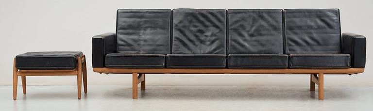 A Hans J Wegner oak and black leather four-seated sofa and stool, Getama, Denmark 1960's.