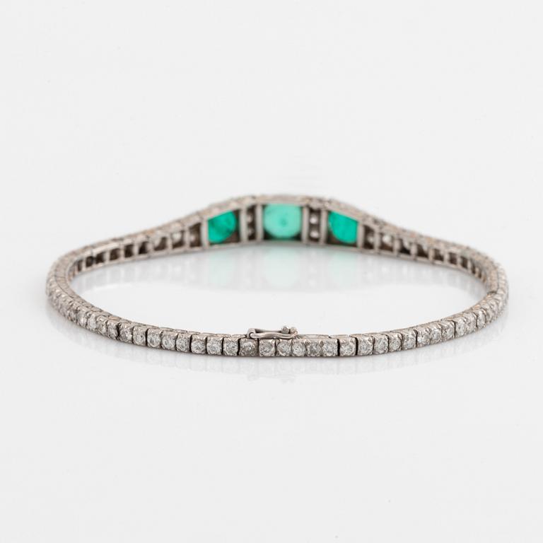 A platinum bracelet set with emeralds and round brilliant-cut diamonds.