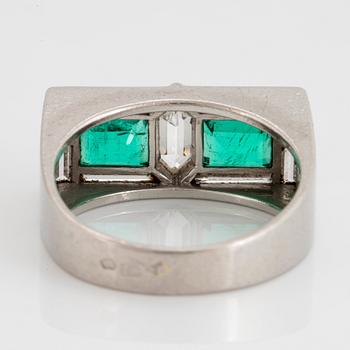 A platinum ring set with faceted emeralds and diamonds.