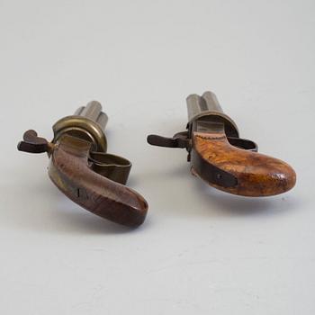 SLAGLÅSREVOLVRAR, 2 st, svenska, i mässing, fyrpipiga, varav 1 signerad.