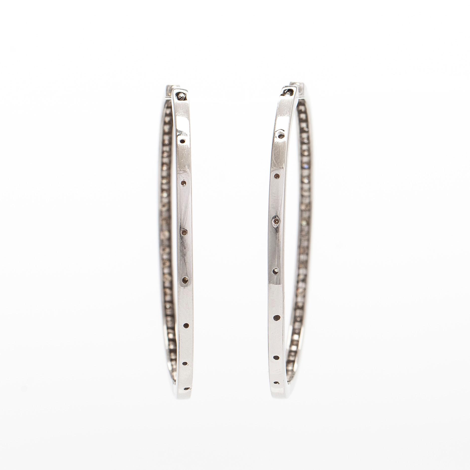 A pair of 14K white gold  hoop earrings with diamonds.