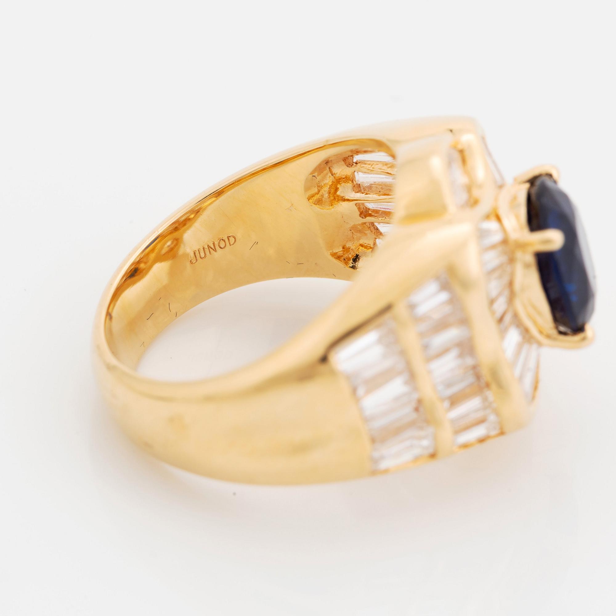 An 18K gold Junod ring set with a facted sapphire and tapered baguette-cut diamonds.
