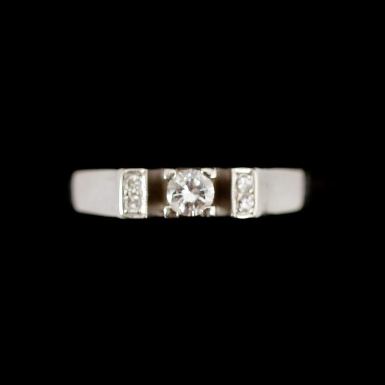 RING, 18 k vitguld, med en större och 4 mindre briljanter, 0.14 ct enligt gravyr. Total vikt ca 3 gram.