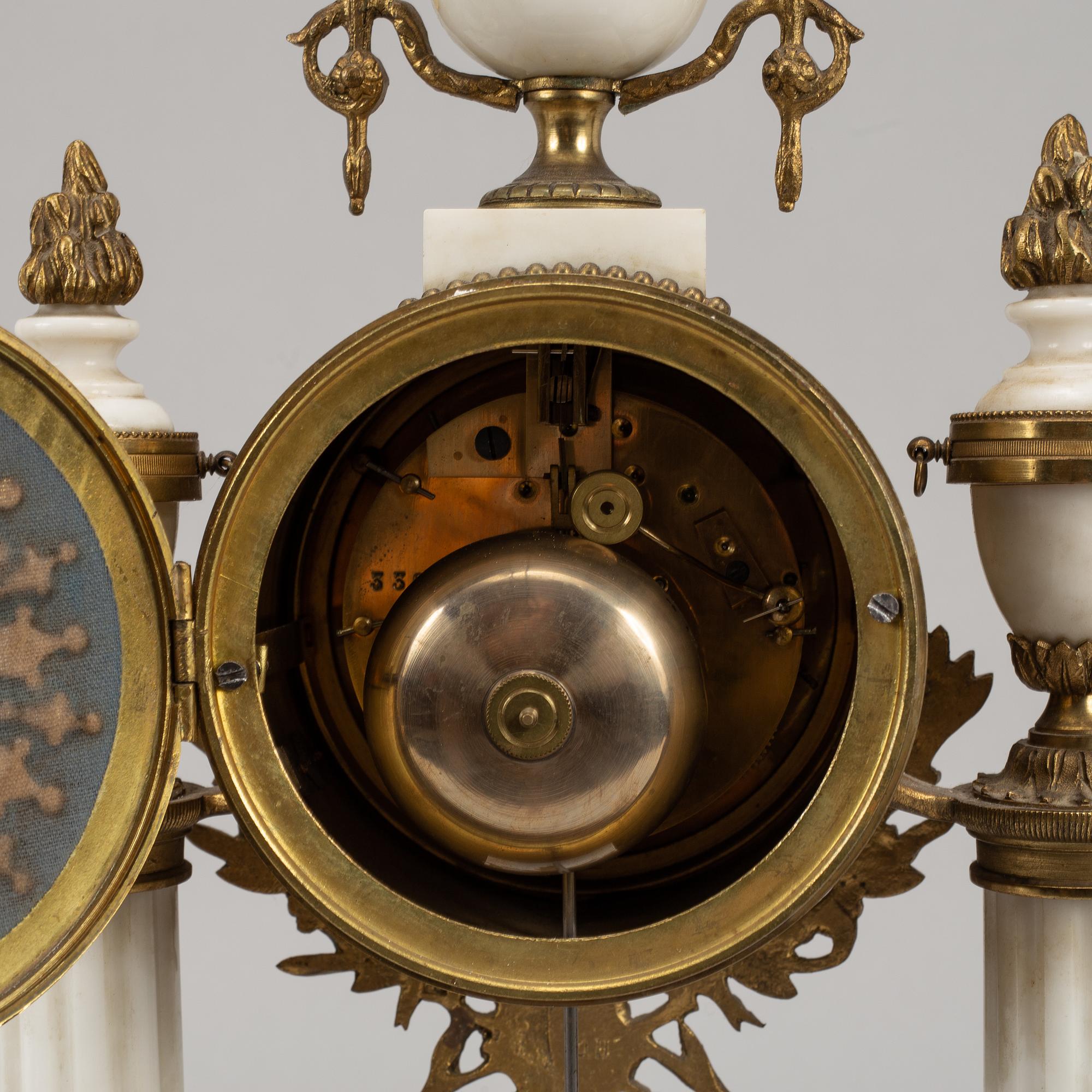A Louis XVI style pendulum clock and a pair of candelabra, early 20th century.