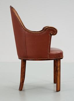 A Swedish easy chair in stained birch, upholstered in artificial leather, by NK, Nordiska Kompaniet, 1910's-20's.