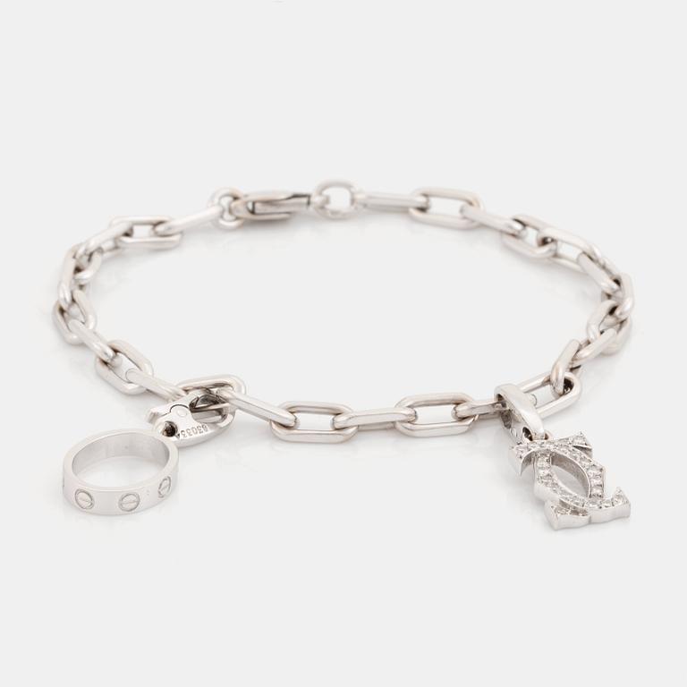 An 18K white gold Cartier "Spartacus" bracelet with two charms.