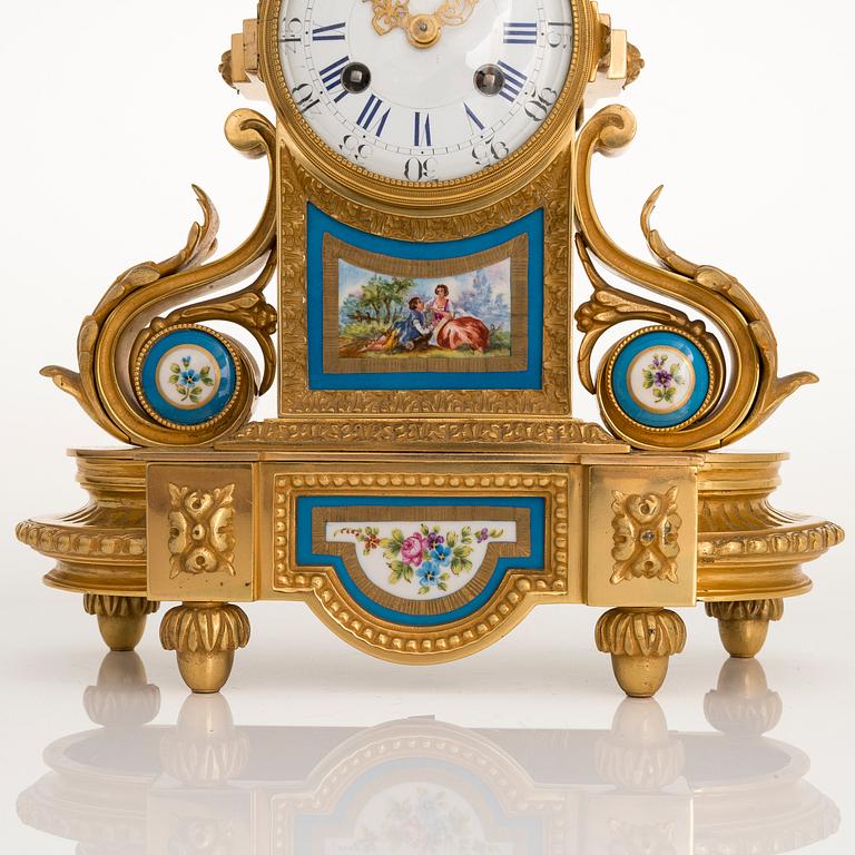 A mid-19th-century French gilt-brass mantel clock with a pair of candelabra by Dussault.