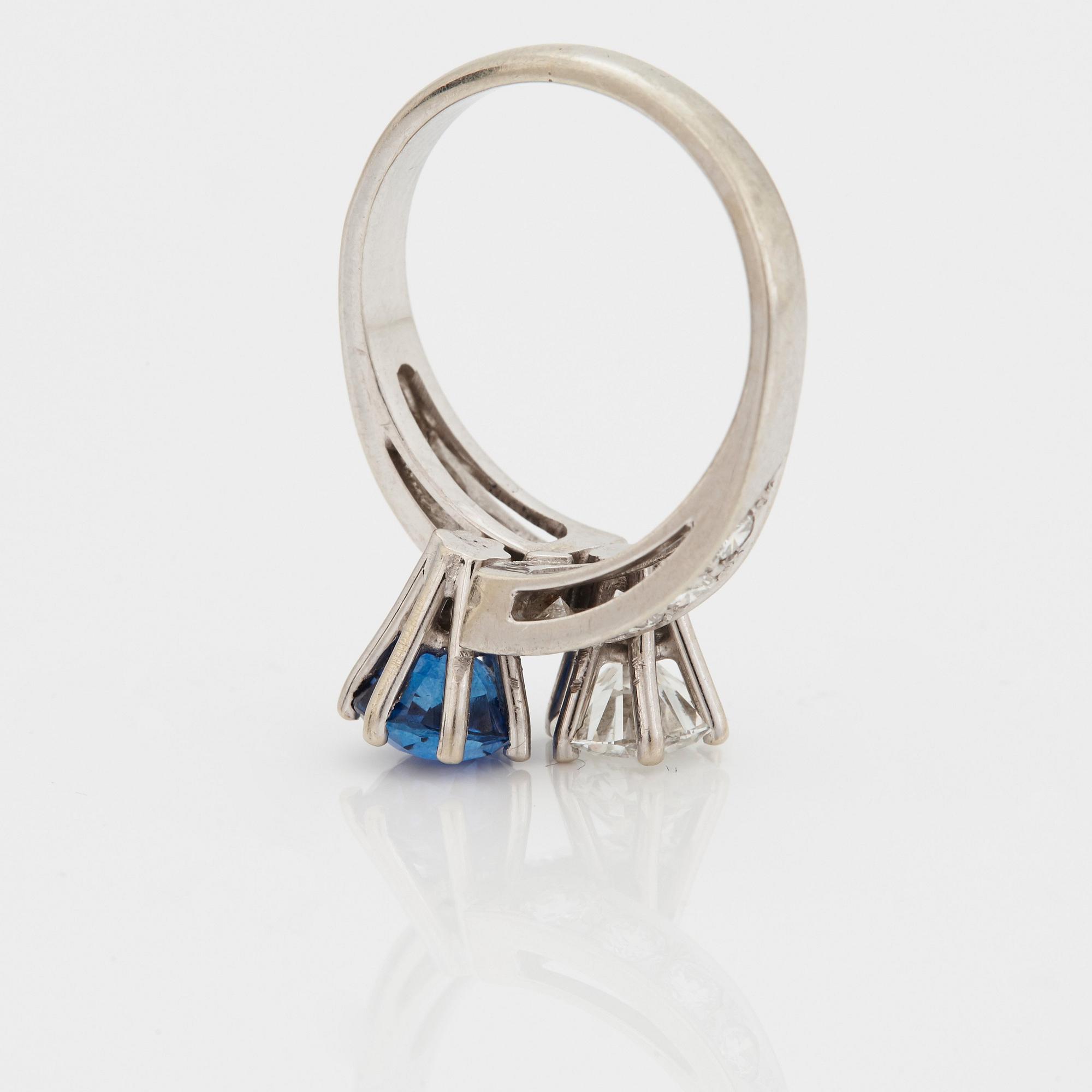 A CROSS-OVER RING set with a round mixed-cut sapphire and round brilliant-cut diamonds.