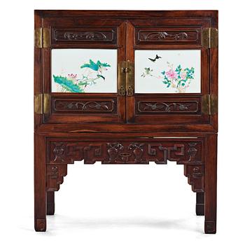 599. A Chinese wooden cabinet with two porcelain placques, early 20th Century.