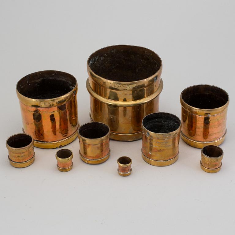 A set of nine brass measures, The Oriental Metal Pressing Works, Ltd, Bombay, Indien, 20th Century.