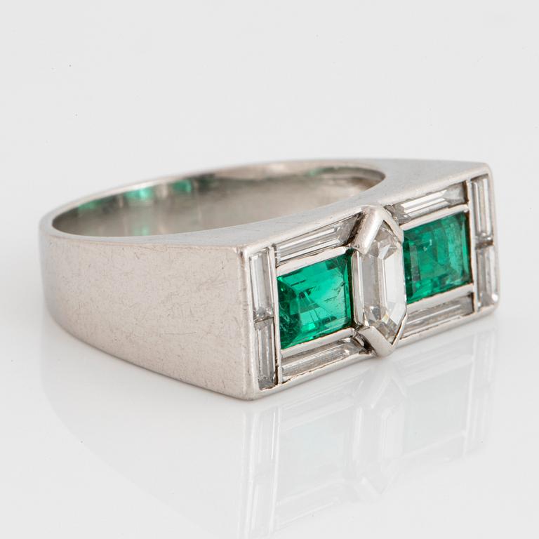 A platinum ring set with faceted emeralds and diamonds.