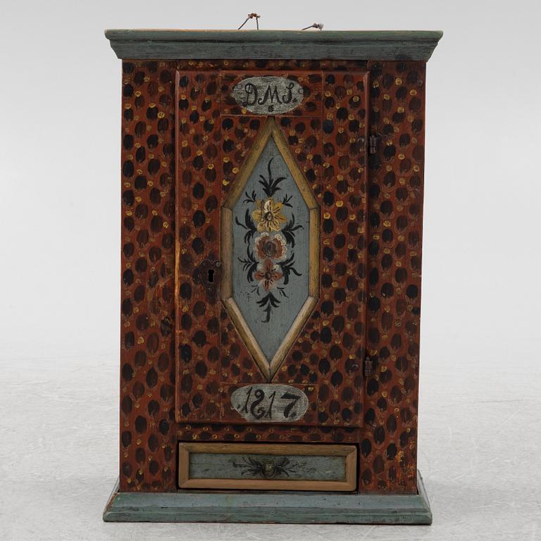 A painted wall cabinet, dated 1817.