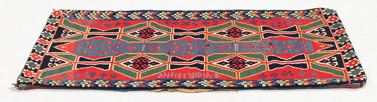 A carrige cushion, 'Träd och timglas', double-interlocked tapestry, c. 102 x 53 cm, signed BID IÅ, dated 1807.