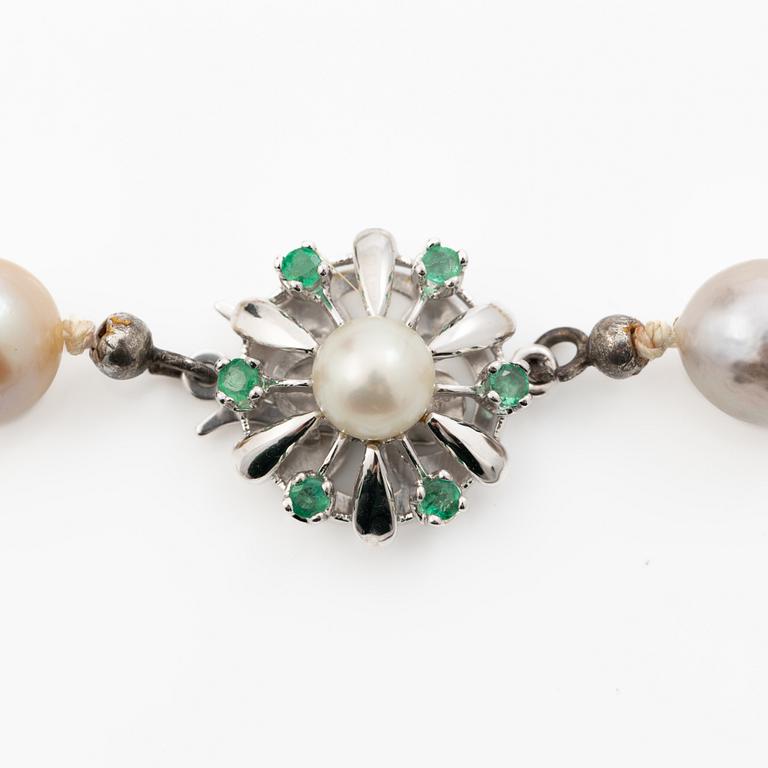 Long cultured pearl necklace with an 18K white gold clasp set with emeralds.