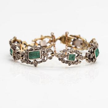 A 14K gold, silver bracelet with emeralds and diamonds.