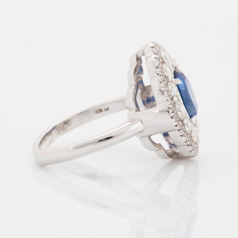 A platinum ring set with a faceted sapphire and round brilliant-cut diamonds.