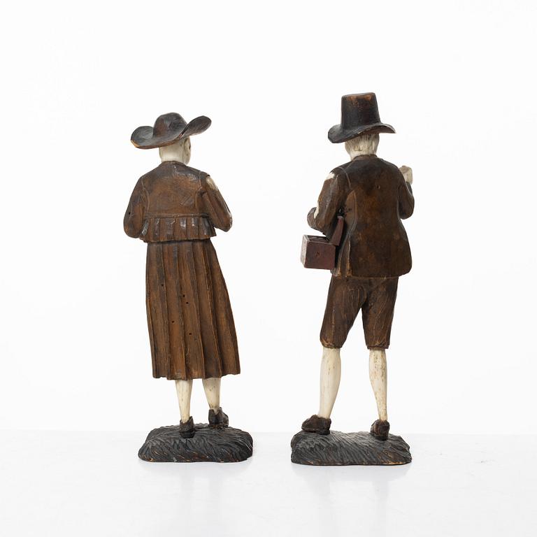 A pair of German carved bone and limewood figures by a follower of Simon Troger, early 18th century.