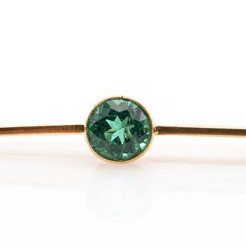 Brosch 18K guld med en runt fasetterad grön turmalin.