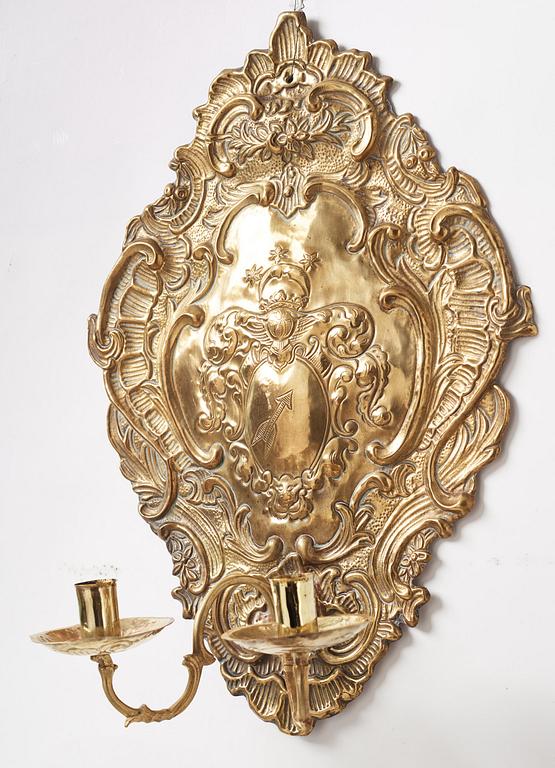 A pair of North European Rococo two-branch repoussé brass reflector plates, mid 18th century.