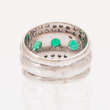 An 18K white gold ring set with oval cut emeralds and round brilliant cut diamonds.