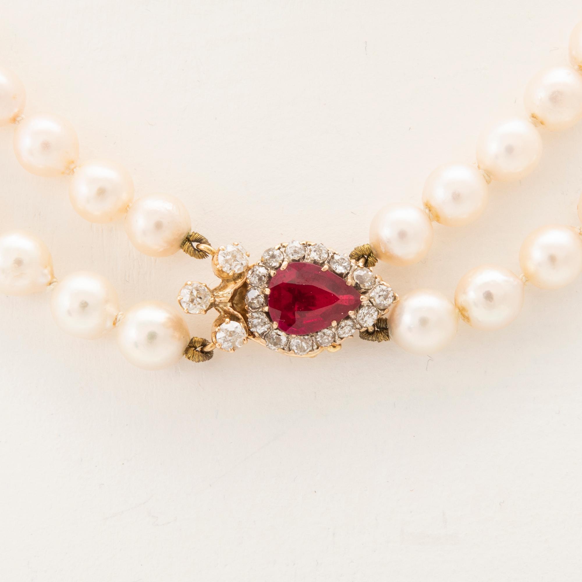 A double-stranded necklace with cultured pearls and an 18K gold clasp with a faceted synthetic ruby and old-cut diamonds.