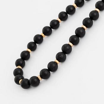 An onyx necklace, a pair of 18K gold earrings with two pairs of pendants in onyx and wood.