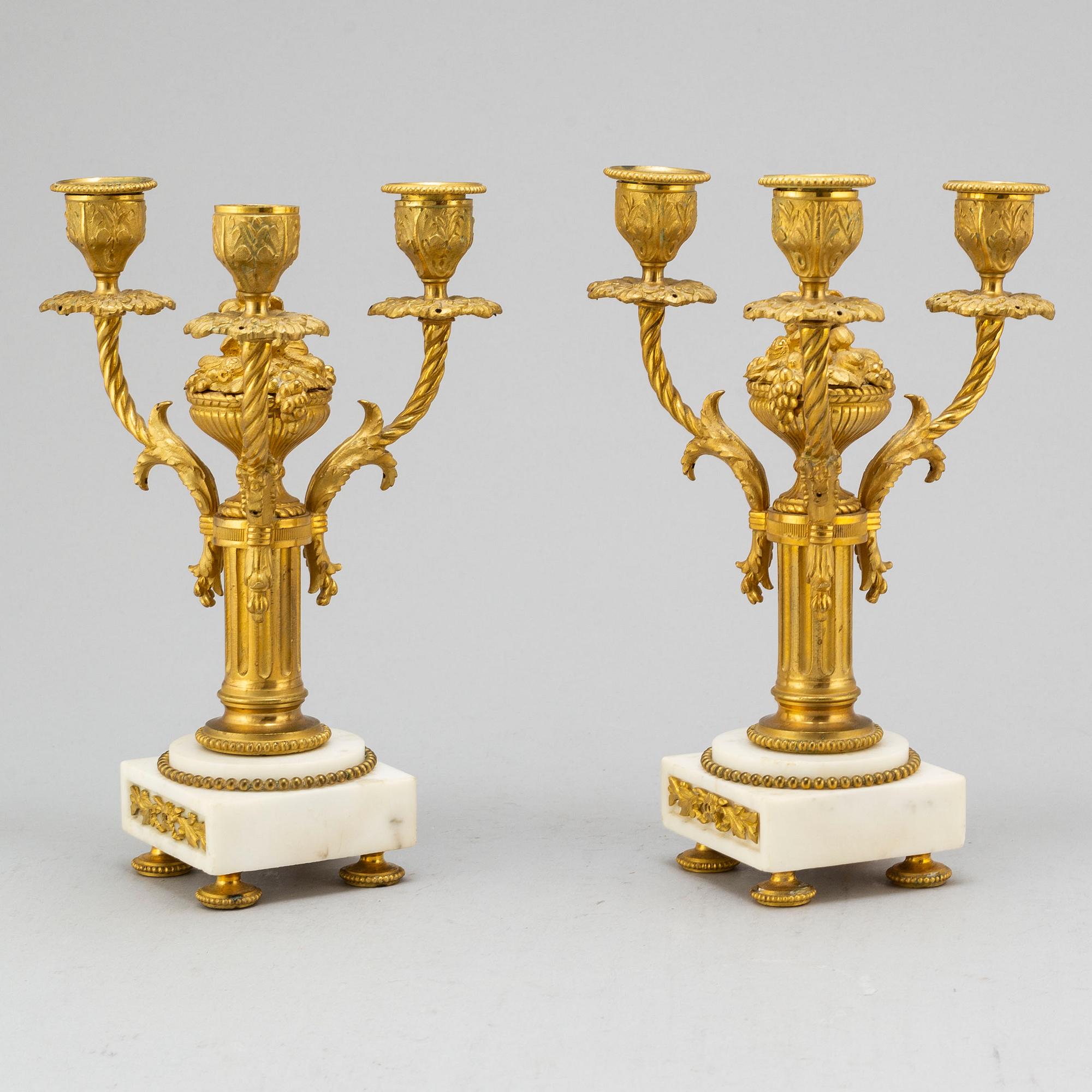 A late 19th century pendulum clock and a pair of candelabras.