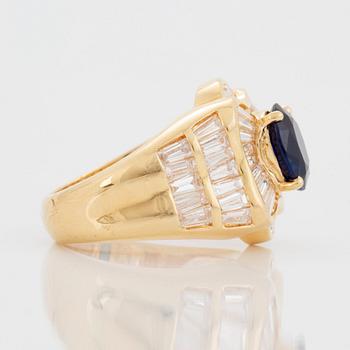 An 18K gold Junod ring set with a facted sapphire and tapered baguette-cut diamonds.