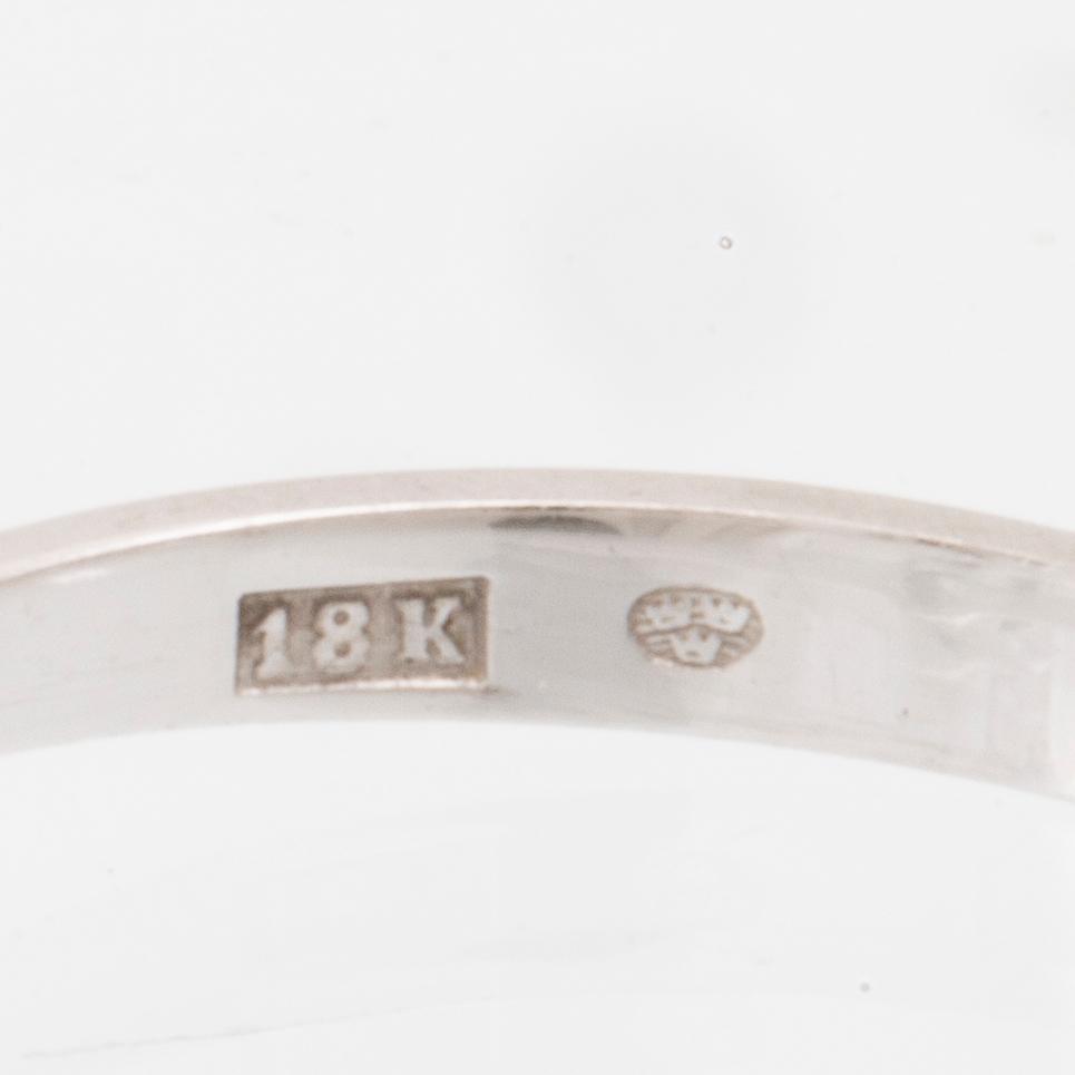 An 18K white gold solitaire ring set with a round brilliant-cut diamond.