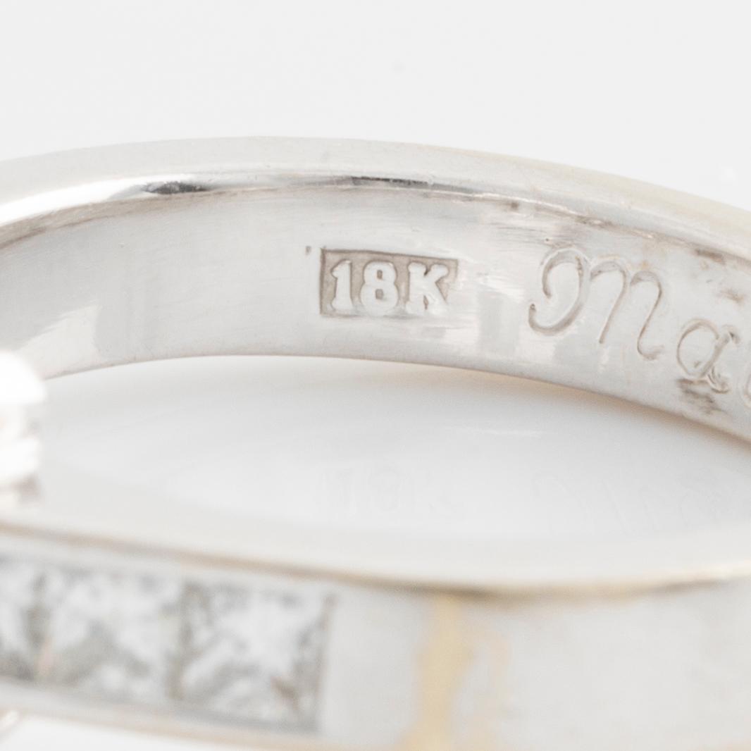 An 18K white gold ring set with an emerald-cut diamond.